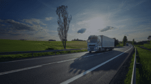 Semi Trailers driving down a road next to green fields