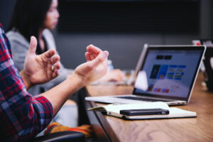 person gesturing in front of a laptop